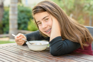 a teenage girl wearing braces eating her soup after braces 